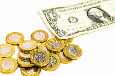 Shiny new one pound coins and one Dollar note distributed on a white backgroundの写真素材