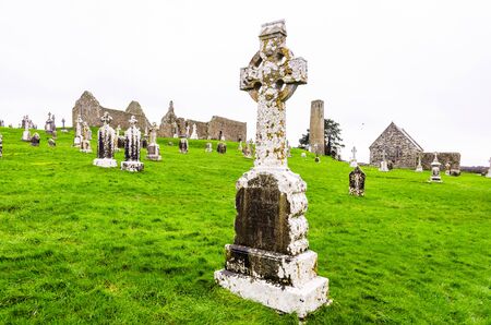 The ancient monastic city of Clonmacnoise with the typical crosses and graves surrounded by green grass, Irelandの写真素材