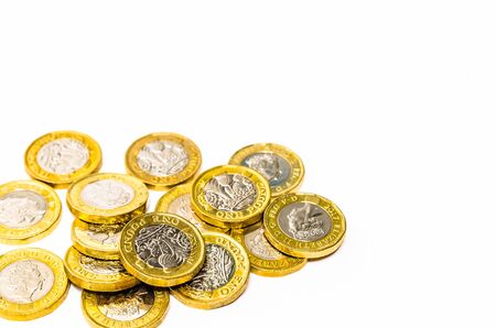 Shiny new one pound coins distributed on a white backgroundの写真素材