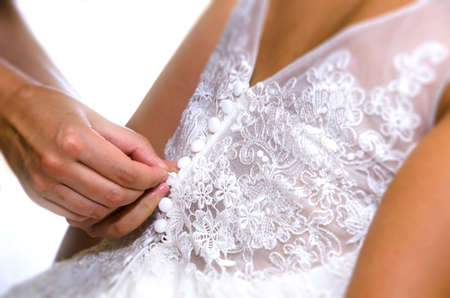 Closing the wedding dress. Close-up image of the traditional momentの写真素材