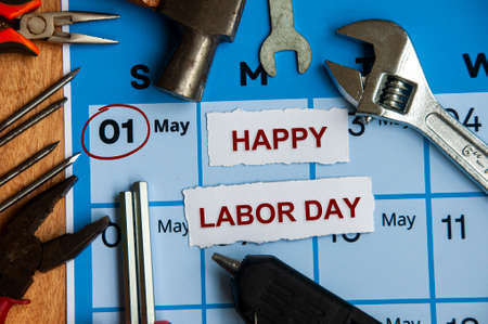 Top view of Happy Labor Day text on torn paper with calendar and working tools background. Copy space and labor day concept.の写真素材