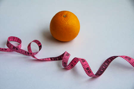 Measuring tape and orange on white background. Weight loss and fitness conceptの写真素材
