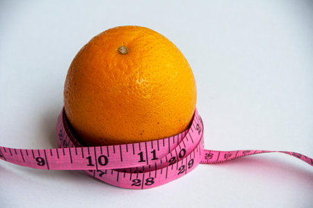 Measuring tape and orange on white background. Weight loss and fitness conceptの写真素材