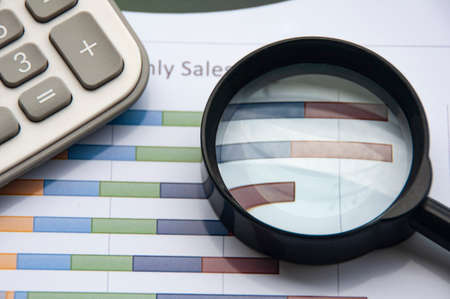 Analysis of data, chart and graphs with calculator and magnifying glass. Business finances and accounting conceptの写真素材