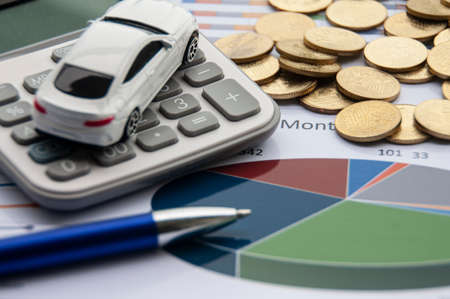 Analysis of data, chart and graphs with isolated calculator, gold coins and toy car. Business finances and accounting conceptの写真素材