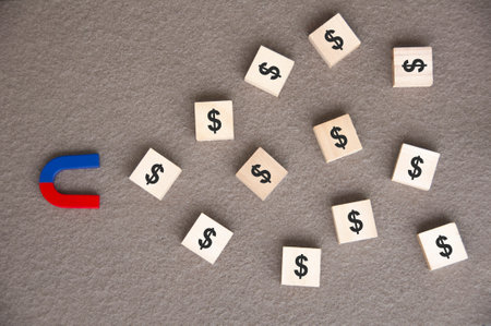 Hand holding magnet attracting wooden dolls on yellow background. Law of attraction concept.の写真素材