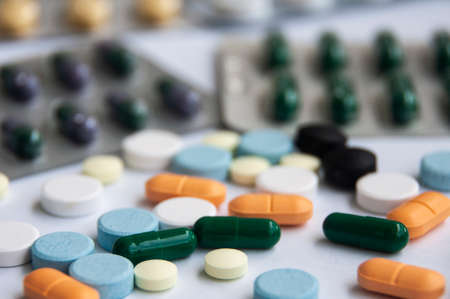 Assorted pharmaceutical medicine pills, tablets and capsules with blurred background over white background. Concept of healthcare and medicine. Copy space.の写真素材