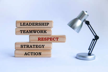 Business text on wooden blocks - Leadership, teamwork, respect, strategy and action. With silver and black small lamp focusing on respect. Business conceptの写真素材