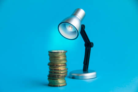 Closeup of gold coins with silver and black small lamp background. Copy space and business conceptの写真素材