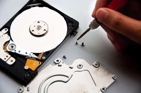 The abstract image of inside of hard disk drive with technician fixing using screw driver on white...