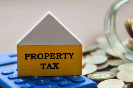 Property tax on wooden model house with calculator and gold coins. Property tax conceptの写真素材