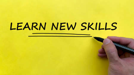 Hand writing a text of learn new skills on yellow background.の写真素材