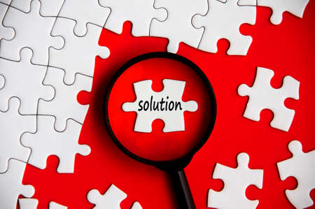 Solution text on missing jigsaw puzzle in magnifying glass. Problem solving conceptの写真素材