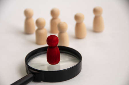 Red wooden doll on top of magnifying glass. Job vacancy and hiring concept. Copy spaceの写真素材