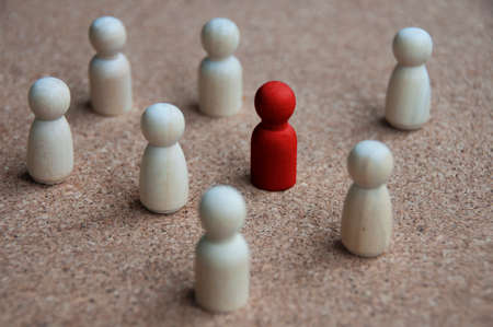 Red wooden doll figure surrounded by other doll figure. Harassment and bully concept.の写真素材