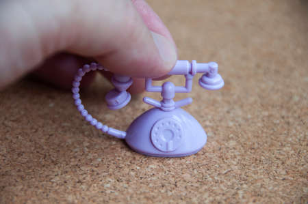 Hand reaching out to analog phone toy on wooden background. Communication conceptの写真素材