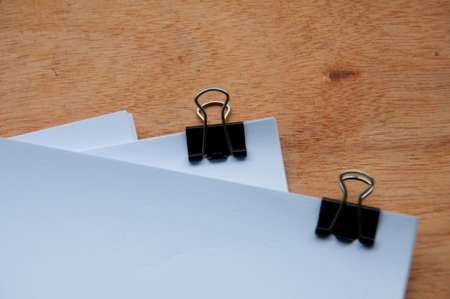 Blank white paper with clip binders on wooden table. Copy spaceの写真素材