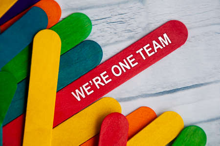 We're one team text on red wooden stick. Teamwork concept