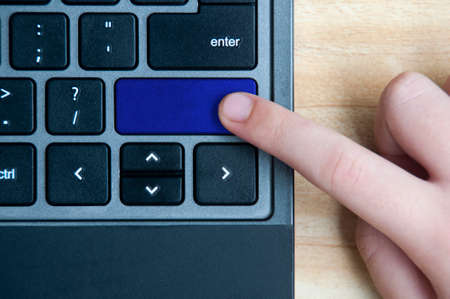 Top view of hand pressing blank blue button on laptop keyboard. Copy spaceの写真素材