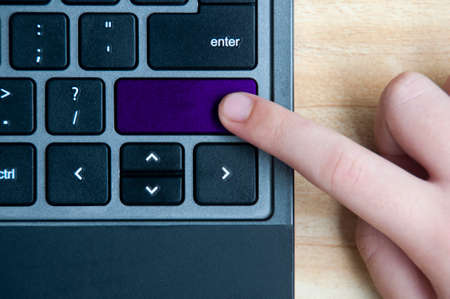 Top view of hand pressing blank purple button on laptop keyboard. Copy spaceの写真素材