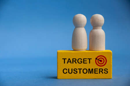 Target customers text on yellow wooden block with model wooden dolls on top.の写真素材