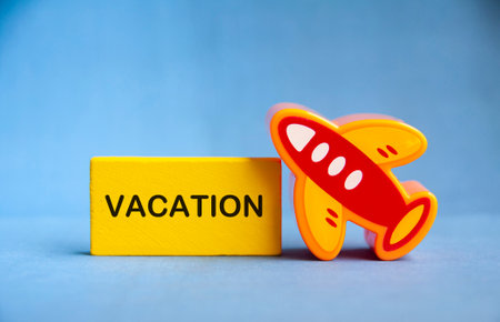 Vacation text on yellow wooden block with toy plane. Travelling conceptの写真素材