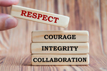 Text on wooden blocks with hand holding one wooden block - Respect, courage, integrity and...