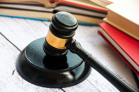 Lawyer gavel on wooden table with wooden desk and books background. Law conceptの写真素材