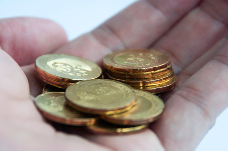 Hand showing gold coins with white background.の写真素材