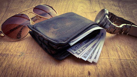Straight view of an old wallet with bank notes. Sun glasses and watch background. Business conceptの写真素材