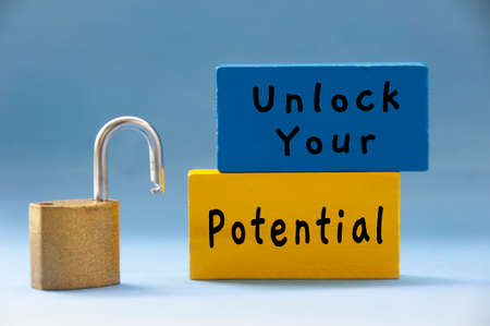 Unlock your potential text on wooden blocks with pad lock on light blue background. Motivational...