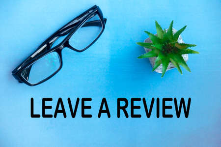 Leave a review text on light blue cover with potted plant and glasses background. Feedback concept.の写真素材