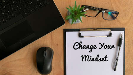 Business motivational quotes - Change your mindset on a piece of paper. With glasses, mouse, plant, laptop and brown table background.の写真素材