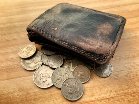 Isolated old coin and leather wallet on brown wooden table.