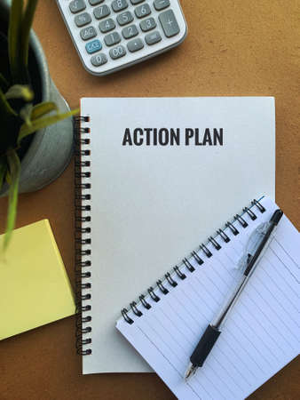 Image with action plan text on a note pad with pen, plant, calculator and sticky note. Business conceptの写真素材
