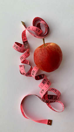 Diet and weight loss Concept. Organic Red apple, weight scale measure tap and white background....