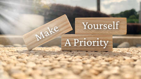Make yourself a priority text on wooden blocks with bright sun and park background. Motivational conceptの写真素材