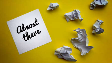 Top view of almost there text on notepad with trash papers and yellow background.の写真素材