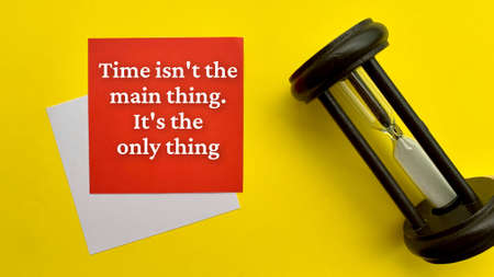 Motivational and inspirational quote - Time is not the main thing. It is the only thing. With yellow cover and hourly glass background.の写真素材
