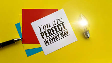 Motivational quote - You are perfect in every way. With notepads and light bulb background. Conceptualの写真素材