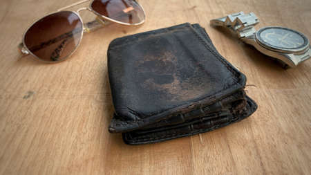 Old wallet on the wooden table with watch and old sun glasses background.の写真素材