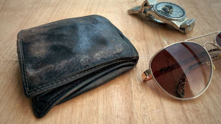 Old wallet on the wooden table with watch and old sun glasses background.の写真素材
