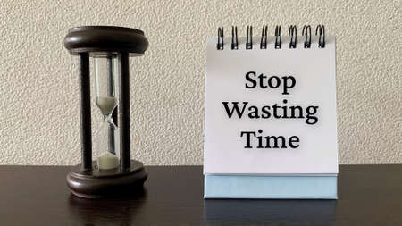 Stop wasting time text on notepad with minutes glass background.の写真素材