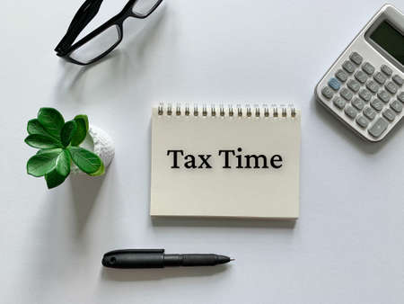 Tax time on notepad with pen, calculator, plant and glasses background.の写真素材