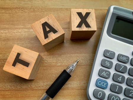 top view of Tax on wooden cube with calculation and pen background.の写真素材