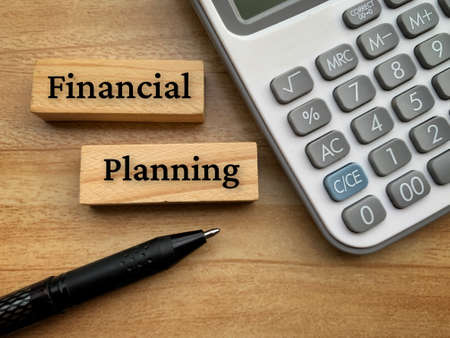 Financial planning text on wooden blocks with calculator and pen background. Conceptualの写真素材