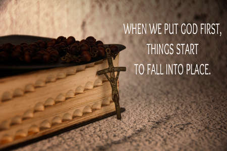 Christian quote - When we put God first, things start to fall into place. with bible and rosary background in vintage color.の写真素材