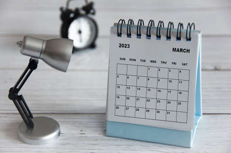 March 2023 white desk calendar with table lamp on wooden table. Calendar conceptの写真素材