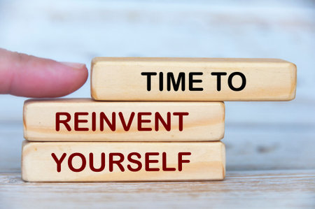 Finger pushing wooden blocks with text - Time to reinvent yourself. Self improvement conceptの写真素材