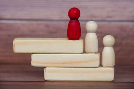 Red wooden doll leading other white wooden dolls with space on wooden blocks customizable for text or ideas. Copy space and leadership conceptの写真素材